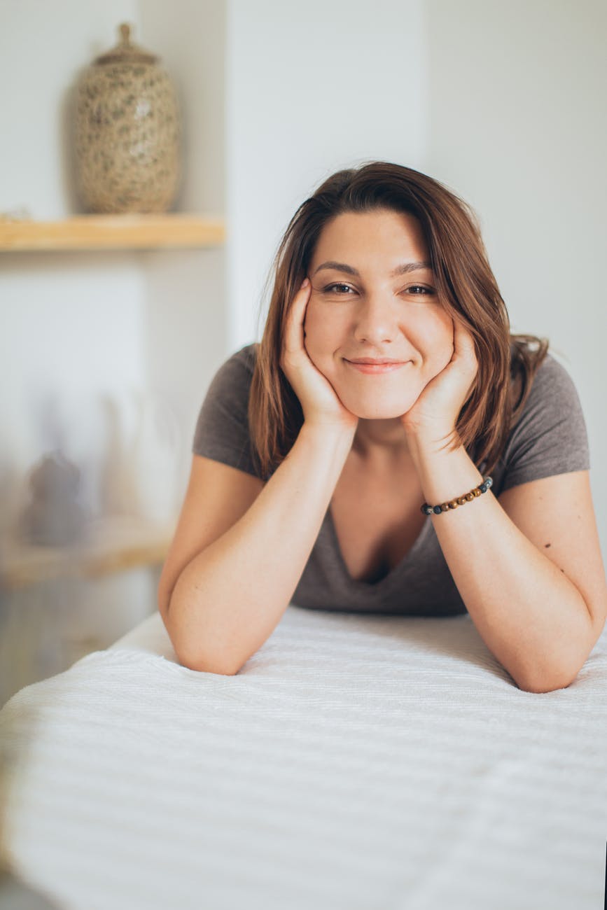 woman in gray shirt lying on a bed